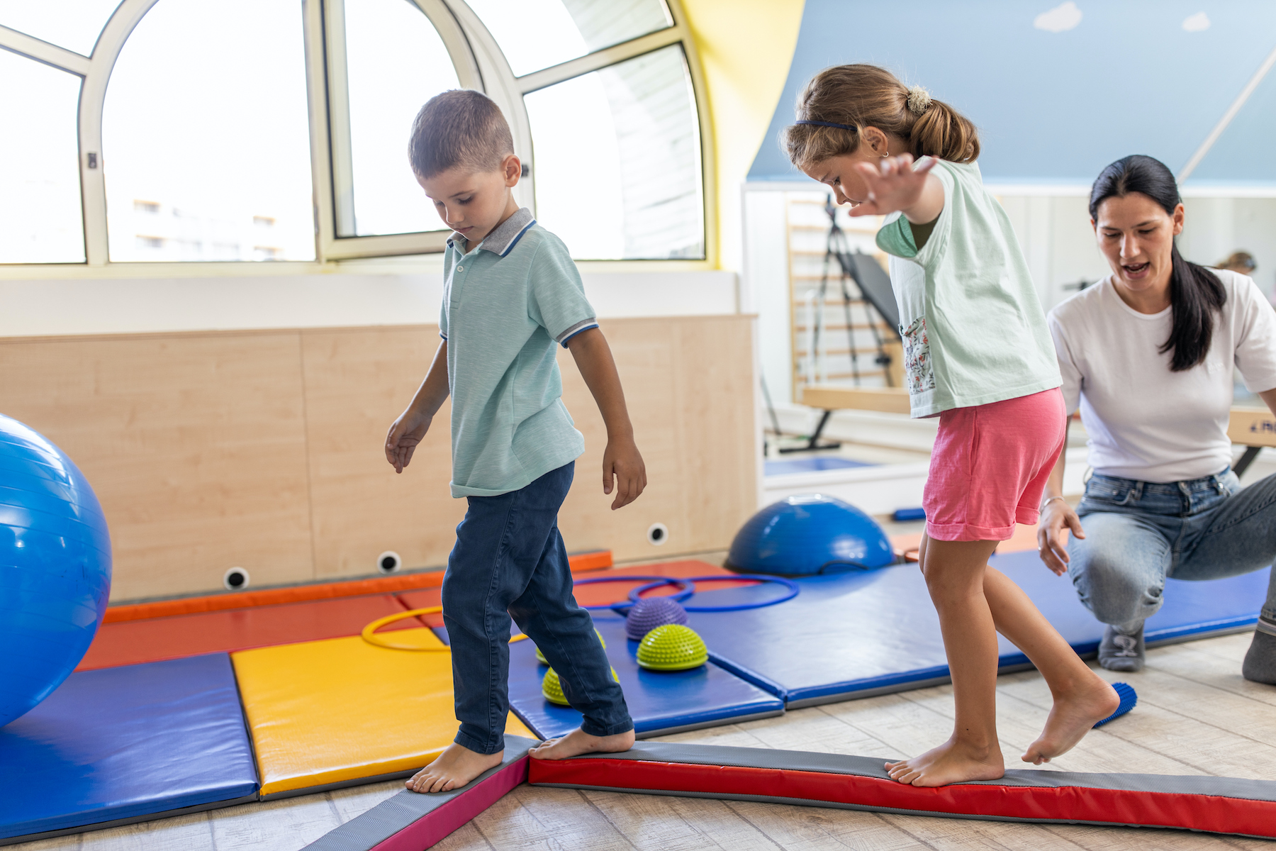 Young females physical therapist working with two kids on clinic